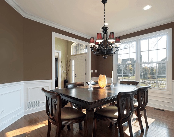 Dining room with warm brown walls and crisp white wainscoting