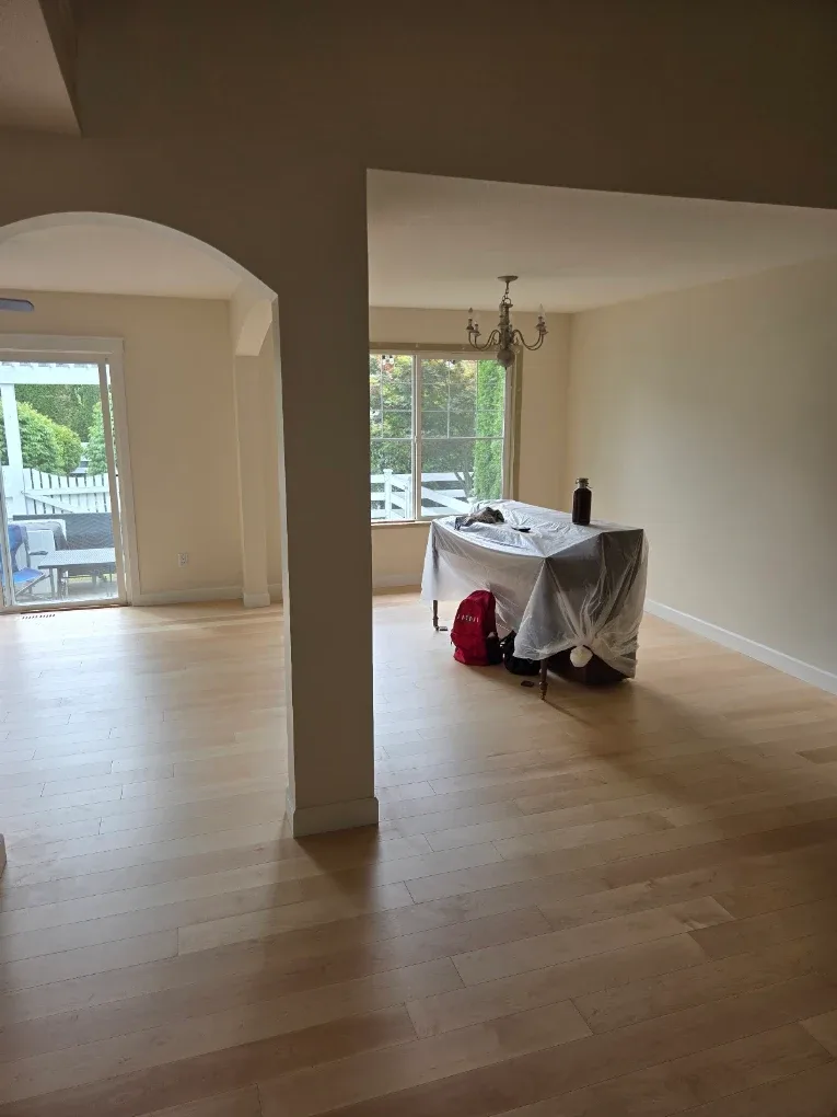 Open plan living and dining room masked and covered part way through an interior repaint