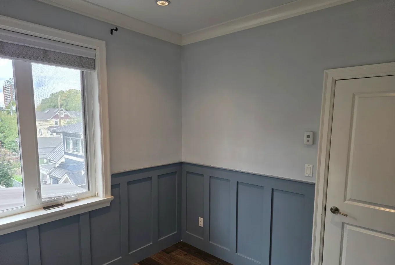 Room finished with blue-grey board and batten wainscoting under pale grey walls